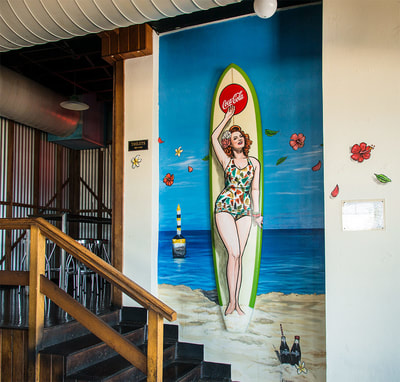 Painted surfboard and mural with Gidget pinup girl 