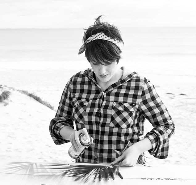 Fieldey painting a surfboard at the beach