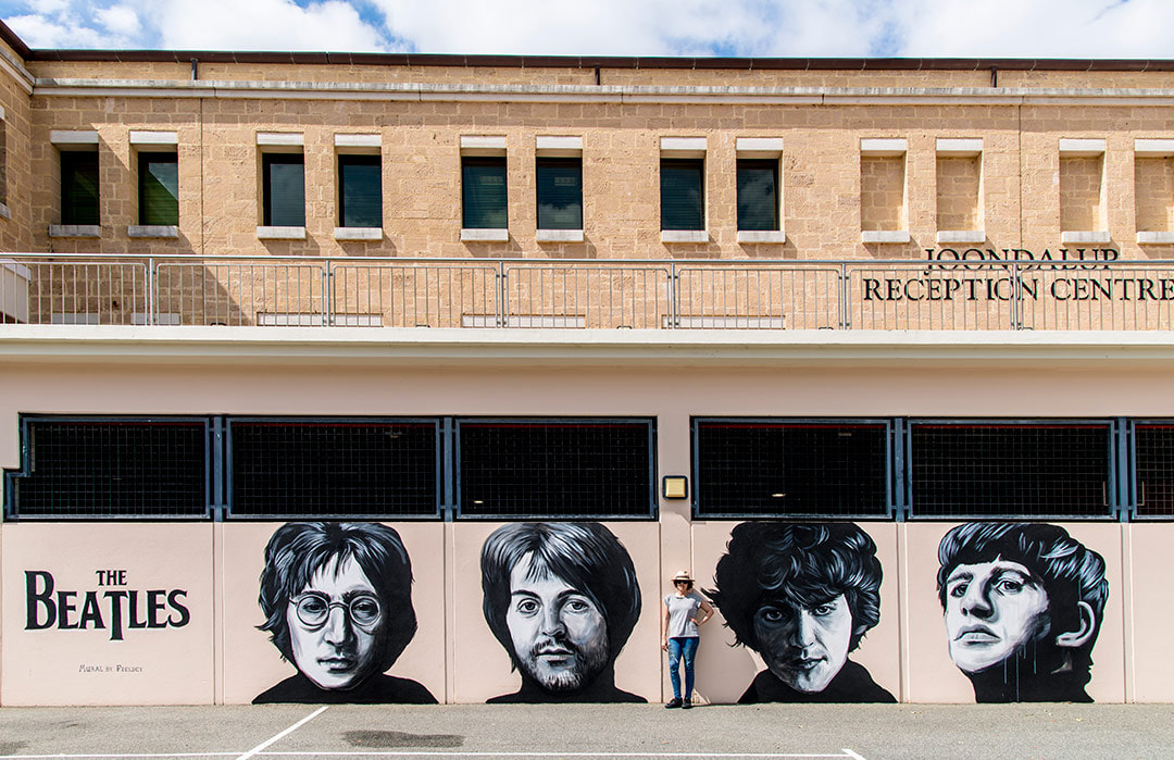 Fieldey standing in front of her large-scale Beatles street art mural painted for Kaleidoscope Festival