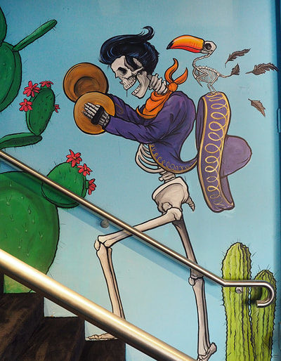 Mariachi skeleton walking up the stairs with a toucan